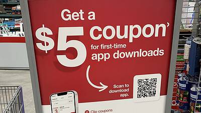 Sign at BJ’s store promoting a $5 coupon for first-time app downloads. Features app benefits like clipping coupons and ExpressPay. A QR code is included.