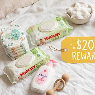 Baby care products including diapers, wipes, and lotion on a soft surface.