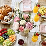Mother's Day brunch table with flowers, fruit, and drinks for a family celebration.