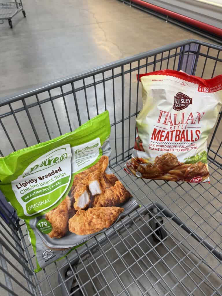 Shopping cart with frozen meatballs and chicken strips at wholesale store.